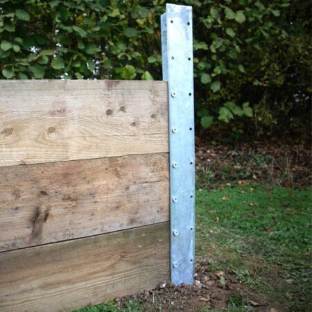 An anthracite grey DuraPost sleeper T-post being used to build a retaining wall. The galvanised steel post features pre-drilled holes for securing heavy wooden sleepers, creating a sturdy and long-lasting garden structure.